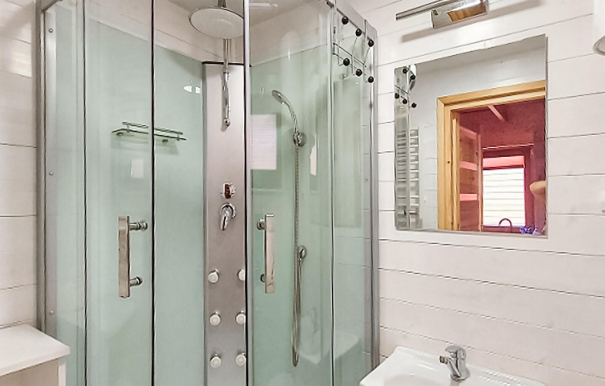 Un bagno moderno con cabina doccia in vetro, una finestra a vista e un lavabo.