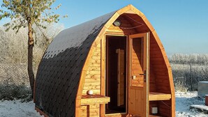 A wooden cabin with a sloped roof, a door, and a small table with a spherical object on it. - Pet friendly home in Postomino with sauna (Postomino)