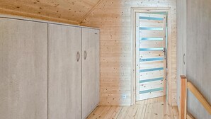 A room with wooden walls and floors, a closed wardrobe, and a door with horizontal blue stripes. - Pet friendly home in Postomino with sauna (Postomino)