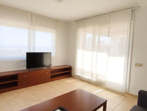 Ein Wohnzimmer mit Fernseher auf einer Holz-Unterhaltungsecke, einer Couch und einer Schiebetür.