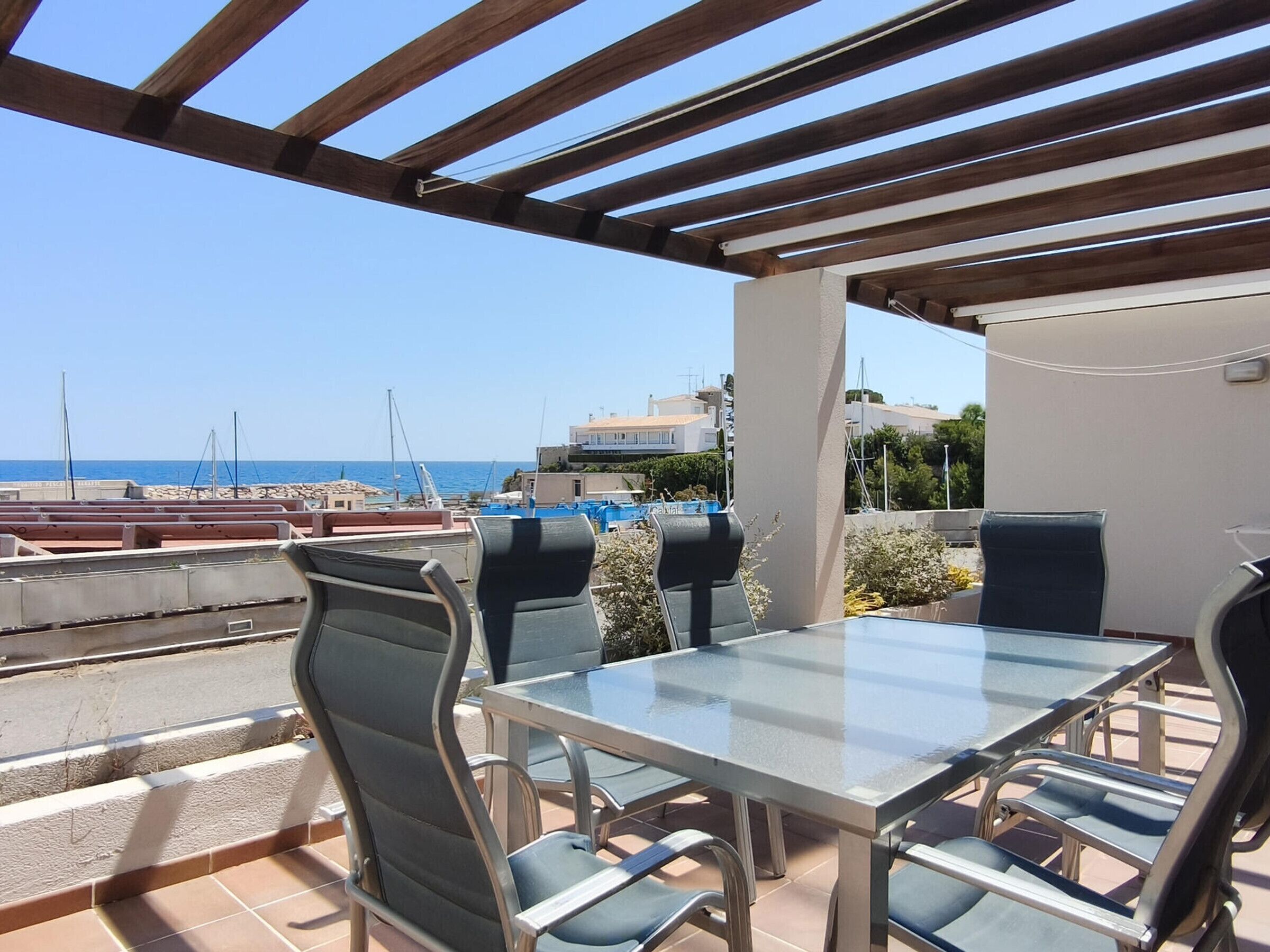 Une terrasse avec une table et des chaises, donnant sur la mer.