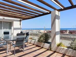 A terrace with a table and chairs, overlooking a marina and the sea. - Luxury Seafront Apartment for Families in L'Ametlla de Mar (L'Ametlla de Mar)