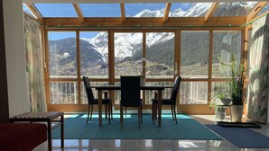 A room with a wooden floor, a dining table with chairs, a small table, and a potted plant. - Apartment with conservatory, wonderful panorama and large terrace (Landeck)