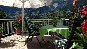 A terrace with a table and chairs under a white umbrella, overlooking a mountainous landscape. - Apartment with conservatory, wonderful panorama and large terrace (Landeck)