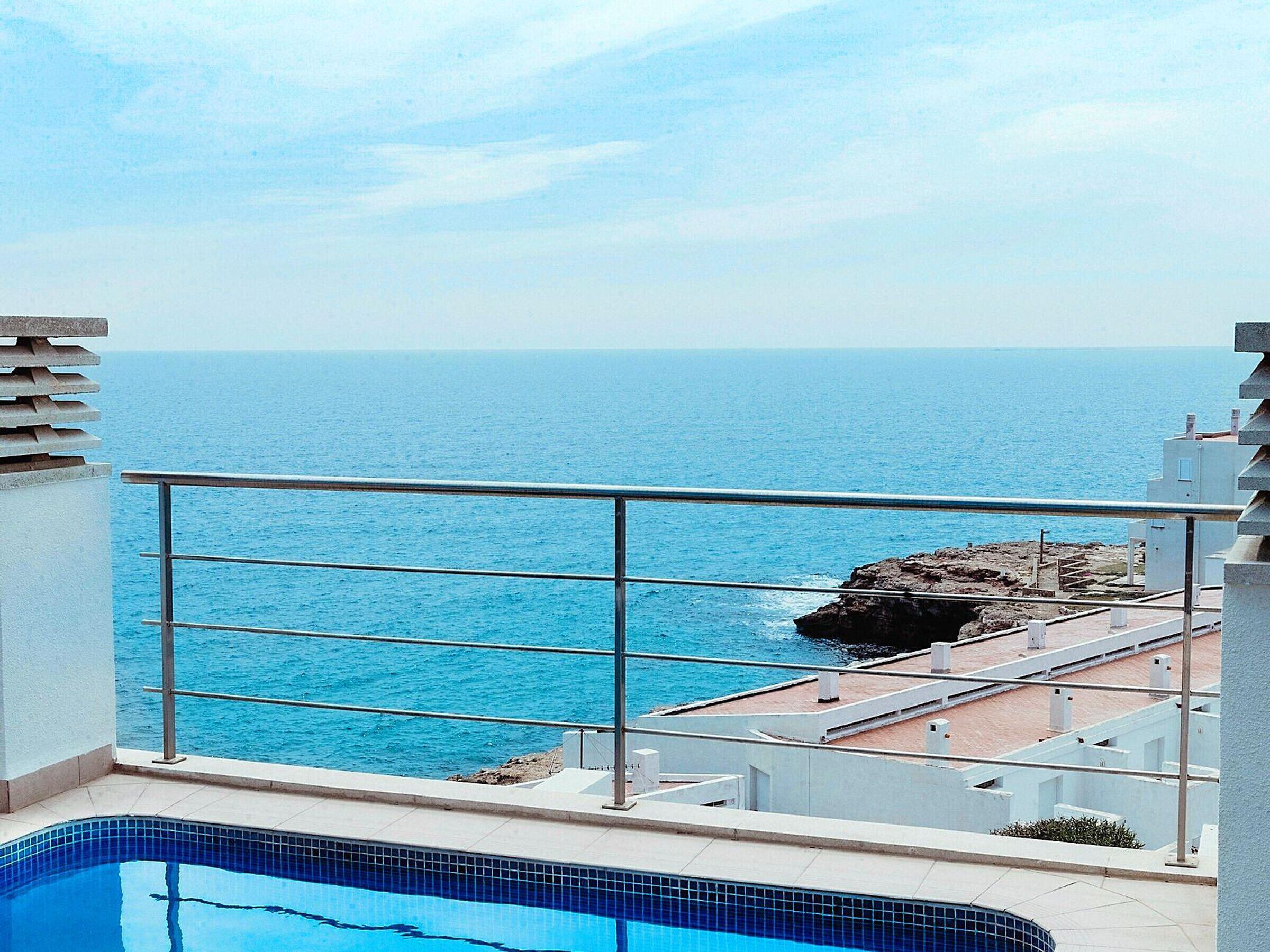 Una piscina con vista al mar y a la costa rocosa.