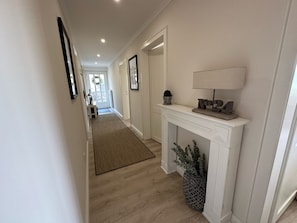 Cozy hallway with a fireplace, framed pictures, and a comfortable rug.