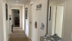 A hallway with a carpet, a welcome sign, a mirror, and a small table with a candle. - Romantic & stylish vacation apartment with two terraces and fantastic views (Höxter)