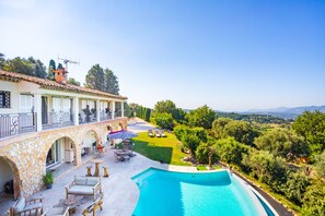 A poolside area with a stone building, outdoor seating, and a view of the countryside. - Le Clos des Senteurs (Chateauneuf-Grasse)