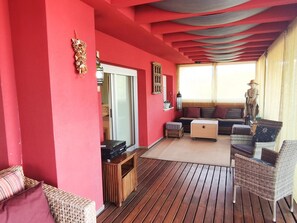 A room with a red wall, wooden flooring, a sofa, a chair, a small table, and a statue.