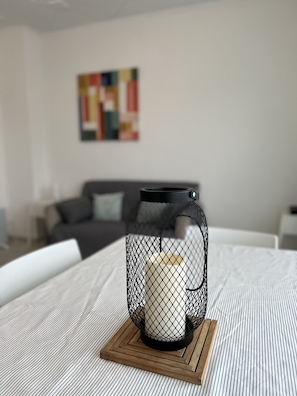 A bed with a white and gray striped bedspread, a black metal candle holder with a white candle, and a wooden coaster.