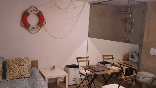 A modern room with a bed, a small table, a desk, and a shower area.