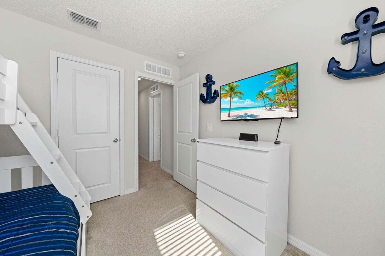 Une chambre à coucher avec un lit, une commode, un téléviseur fixé au mur et un escalier.