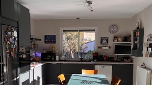 Una cucina moderna con zona pranzo, che include un tavolo con sedie, un frigorifero e una finestra vista esterna.