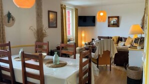 A cozy living room with a dining area, wooden furniture, a TV, and a lamp. - Maison MaxAnne, half village, half authentic countryside (Corrèze)