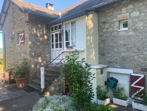 Un edificio de piedra con una puerta blanca, una ventana pequeña y una escalera que lleva a un porche.