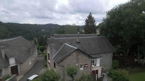 A stone house with a sloped roof, a small garden with a table and chairs, and a view of the surrounding countryside. - Maison MaxAnne, half village, half authentic countryside (Corrèze)