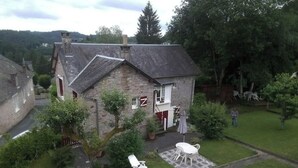 A stone house with a small garden, a lawn chair, and a table. - Maison MaxAnne, half village, half authentic countryside (Corrèze)