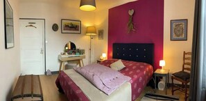 Un dormitorio con cama, mesitas de noche, escritorio y silla.