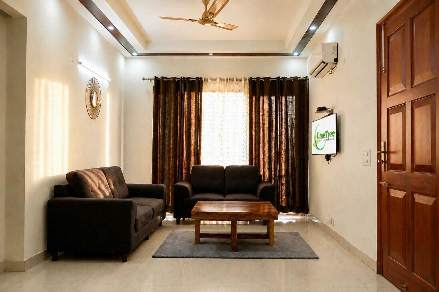 A living room with a sofa, a coffee table, and a television mounted on the wall.