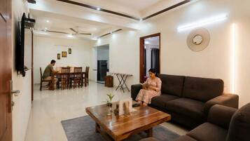 A living room with a sofa, a coffee table, and a dining area with chairs and a table.