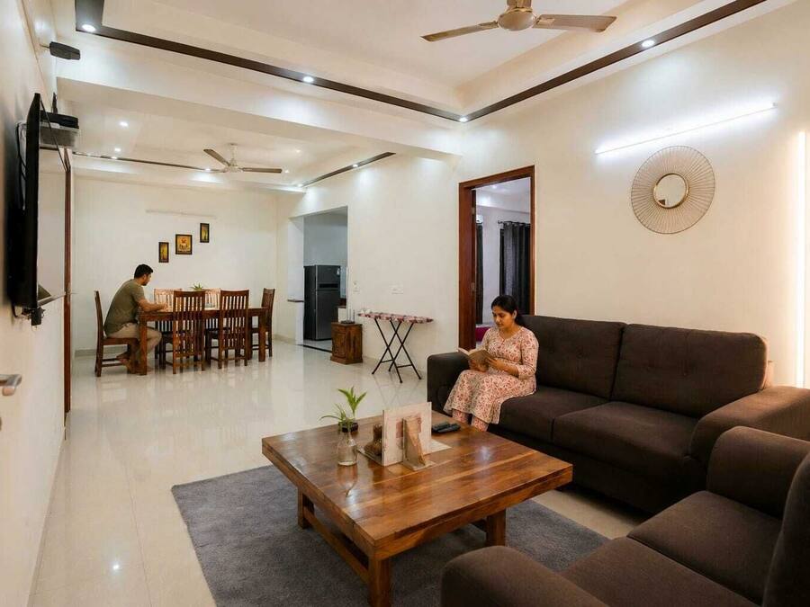 A living room with a sofa, a coffee table, and a dining area with chairs and a table.