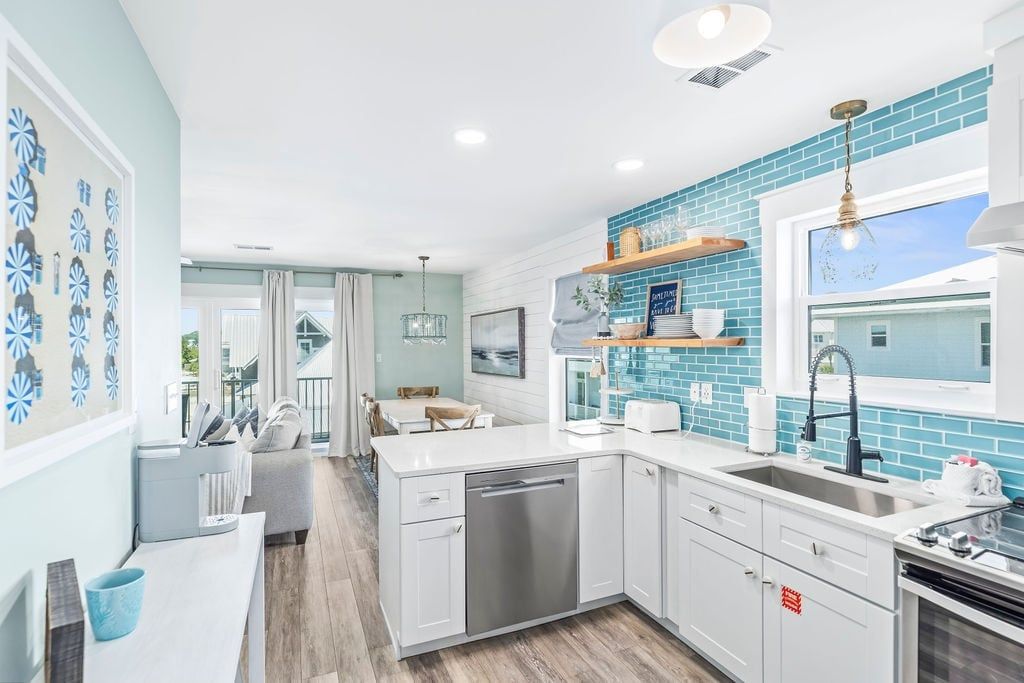 A modern kitchen with white cabinetry, a dishwasher, and a blue-tiled backsplash.
