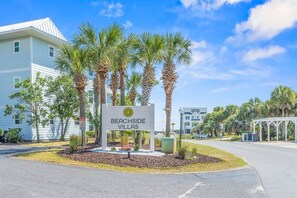 A sign for Beachside Villas with a clear sky and palm trees.