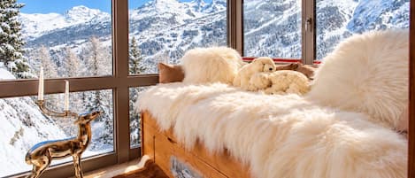 Une pièce confortable avec un lit, une grande fenêtre et une vue sur des montagnes enneigées.