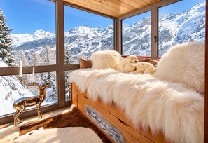 Une pièce confortable avec un lit, une grande fenêtre et une vue sur des montagnes enneigées.
