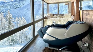 Una camera moderna con un'ampia finestra vista montagna, un letto confortevole e una poltrona massaggiante.