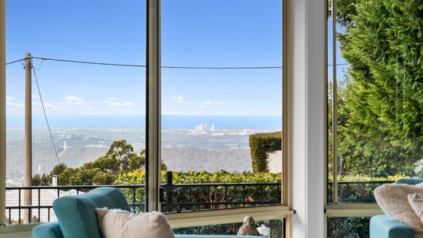 A room with large windows offering a view of a cityscape and greenery.