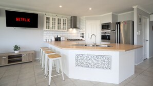 A modern kitchen with a large island, white cabinetry, and a built-in microwave.