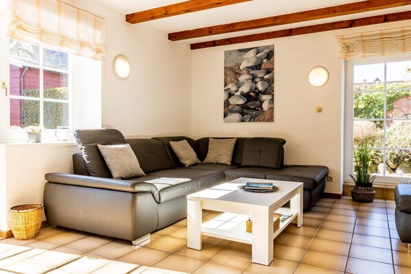 A cozy living room with a sectional sofa, a white coffee table, and a painting of rocks on the wall.