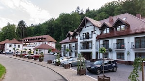 Une rangée d’immeubles à deux étages dotés de balcons, un parking et une route au premier plan.