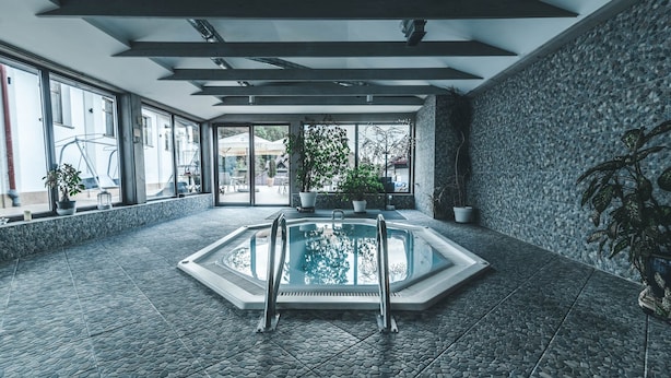 Une piscine intérieure dont le sol est recouvert de carreaux de pierre et qui est équipée d’une échelle en métal.