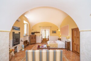 Una habitación acogedora con chimenea, una cama, un sofá y una mesa de comedor.