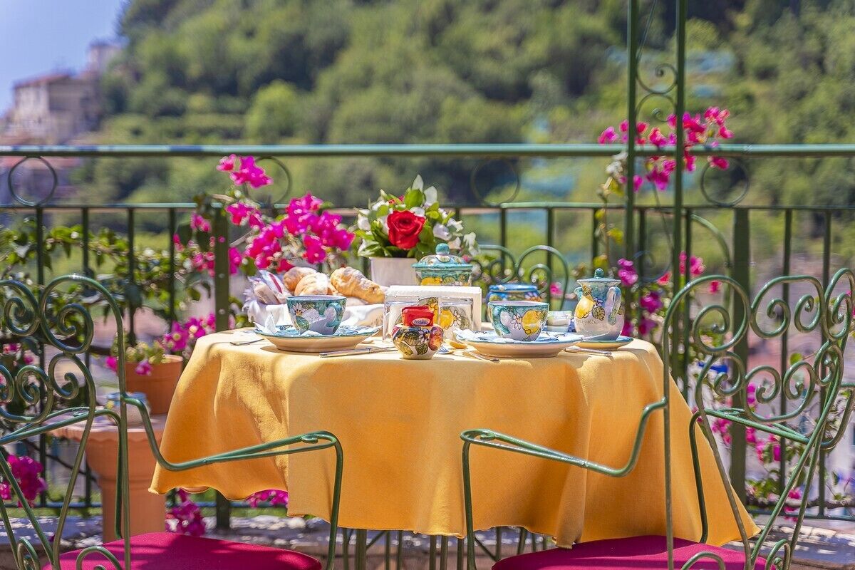 Une table dressée à l’extérieur, recouverte d’une nappe jaune et entourée de chaises vertes.