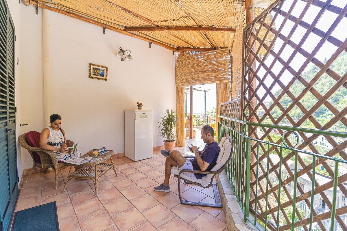 Un espacio al aire libre cubierto con mobiliario de mimbre, un refrigerador y una planta en maceta.