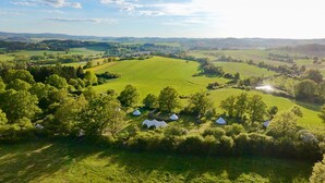 An aerial view of a rural landscape with several white tents and a large open field. - Glamping in Stunning Bell Tent in Bohemia (Čmelíny)