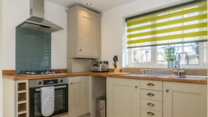 A kitchen with a gas stove, oven, and a window with yellow blinds. - Stunning 4 Bed Sleeps 8 Cottage Parking (Gloucester)