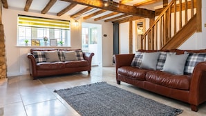 A living room with two brown leather sofas, a grey rug, and a wooden staircase. - Stunning 4 Bed Sleeps 8 Cottage Parking (Gloucester)