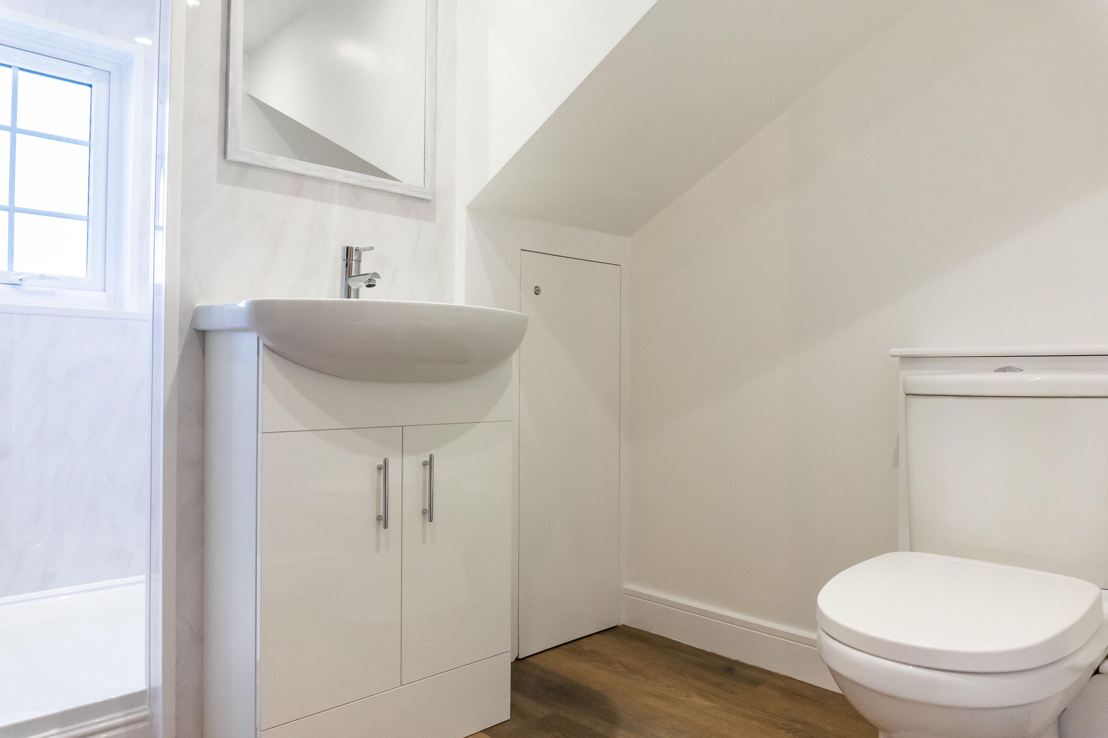 A bathroom with a white sink, a toilet, and a cabinet with two drawers.