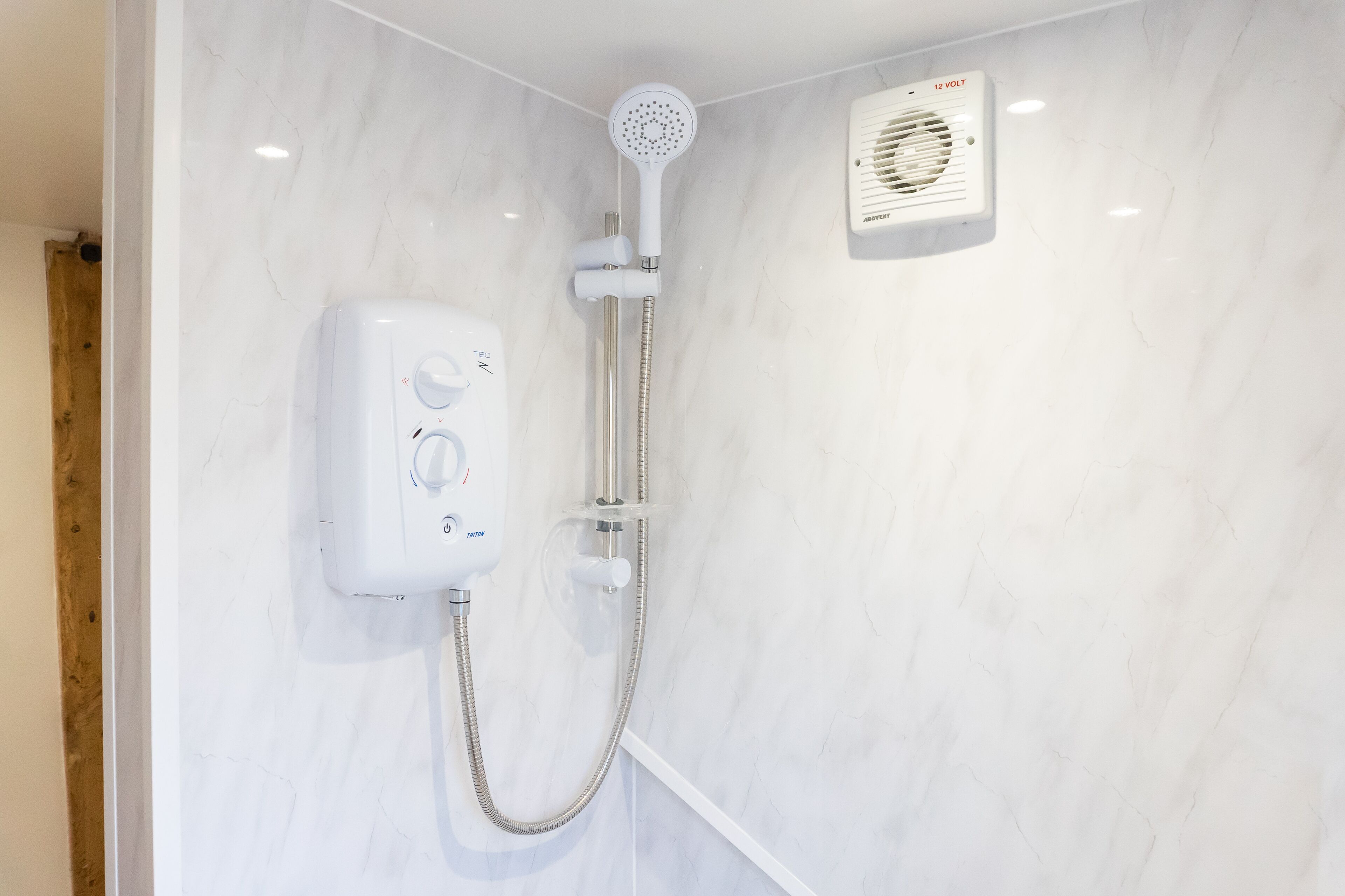 Een moderne badkamer met een inloopdouche, een handdouche en een bedieningspaneel aan de muur.