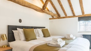 A neatly made bed with white and green bedding, a bedside lamp, and a window with a view of a building. - Stunning 4 Bed Sleeps 8 Cottage Parking (Gloucester)