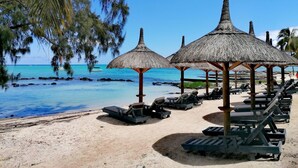 A beach with thatched umbrellas, lounge chairs, and a clear view of the ocean. - Wonders Beach Boutique Hotel (Mont Choisy)