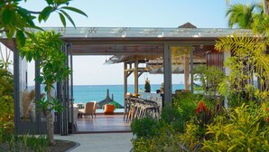 A covered outdoor seating area with a view of the sea, featuring a bar and chairs. - Wonders Beach Boutique Hotel (Mont Choisy)