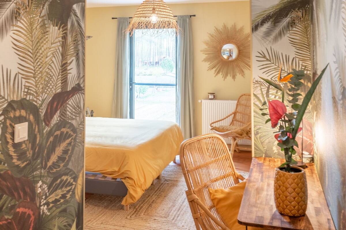 Ein Zimmer mit einem Bett, einem Korbsessel und einem Tisch mit einer Ananas-Vase.