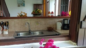 A kitchen with a sink, a coffee maker, and a bowl of fruit on the counter.