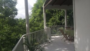 A covered outdoor area with a railing, a table, and chairs.