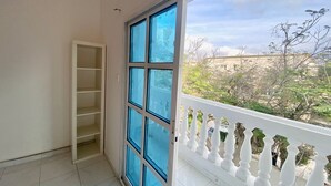 A balcony with a white balustrade, a large window with blue panes, and a white tiled floor. - Villa 126 (Dubai)